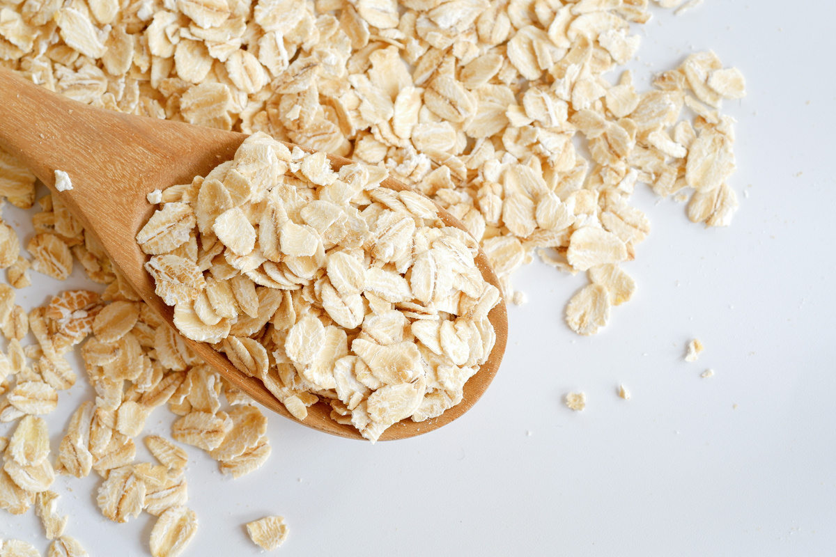Rolled oats in a wooden spoon on a oats pile.